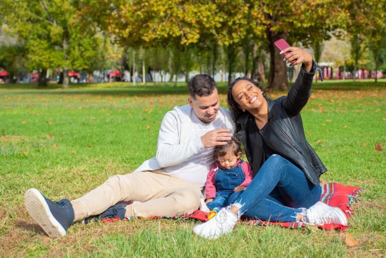 A happy Indian multi-generational family taking a selfie with the Auckland Sky Tower in the background, celebrating their New Zealand group vacation.