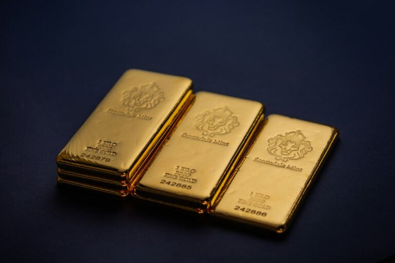 Three one-kilo gold bars stacked on a dark surface