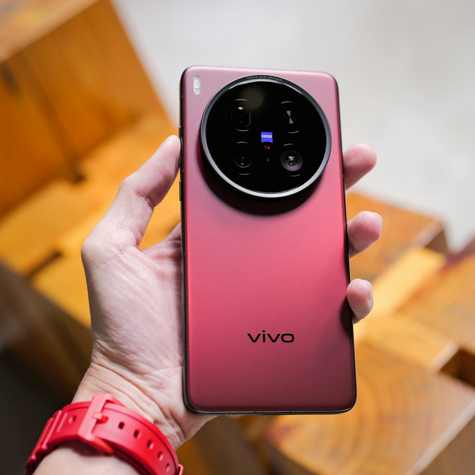 A person holding a red Vivo smartphone - stock photo