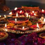 Decorated diyas, traditional oil lamps, lit among flower petals for Diwali