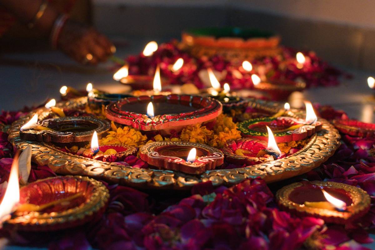 Decorated diyas, traditional oil lamps, lit among flower petals for Diwali